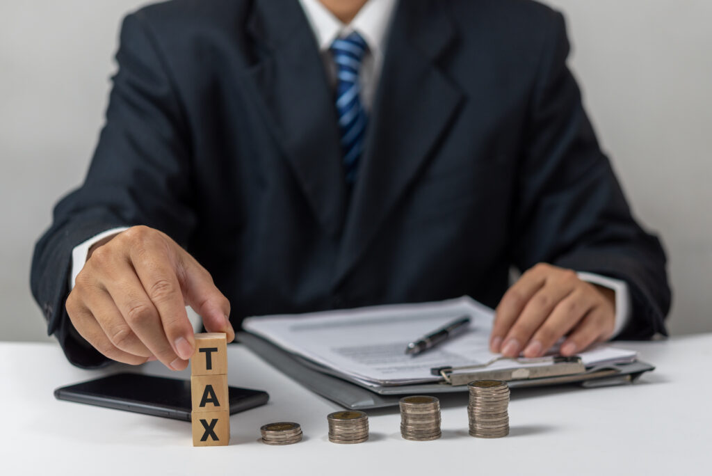 Businessman holding Wood Cube Tax Coin Financial Concept Design with a stack of coins. Business fina